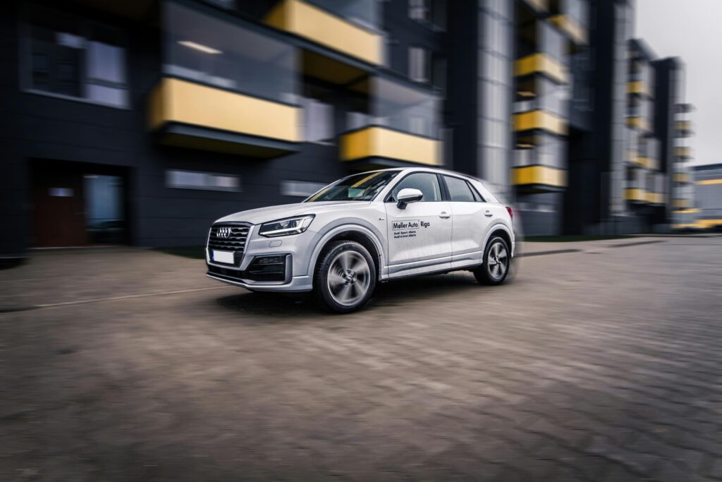 A dynamic shot of a modern Audi SUV speeding through a contemporary cityscape.